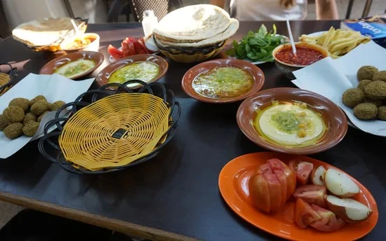 Tafel vol Midden-Oosters eten met hummus, falafel, groente, pita’s en sausjes.