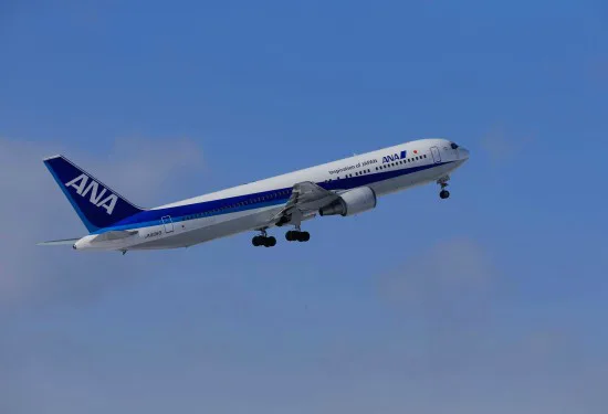 Een passagiersvliegtuig van luchtvaartmaatschappij ANA stijgt op tegen een blauwe lucht.