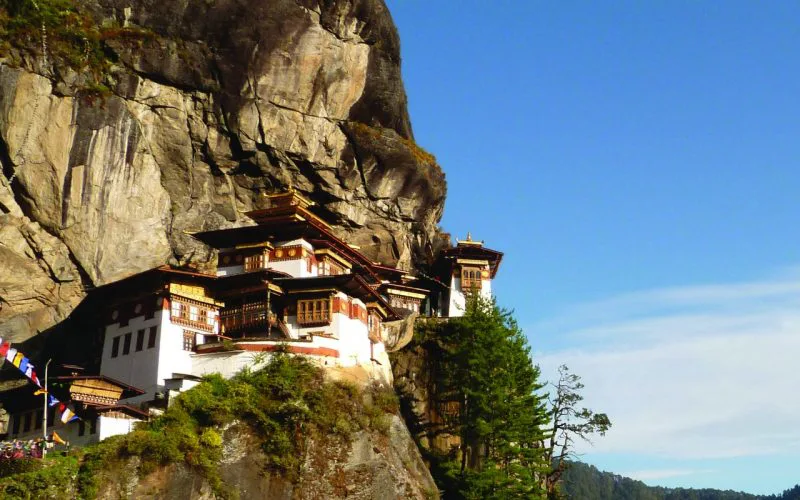 Het Tiger’s Nest-klooster in Bhutan, gebouwd tegen een steile rotswand met uitzicht over een bosrijk dal.