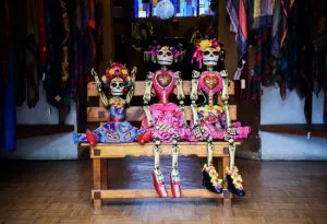 Gekleurde skelettenpoppen in traditionele kleding zitten op een bankje ter ere van Día de los Muertos.