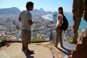 Twee mensen staan op een uitzichtpunt boven Rio de Janeiro, met uitzicht over de stad, stranden en de beroemde Suikerbroodberg op de achtergrond.