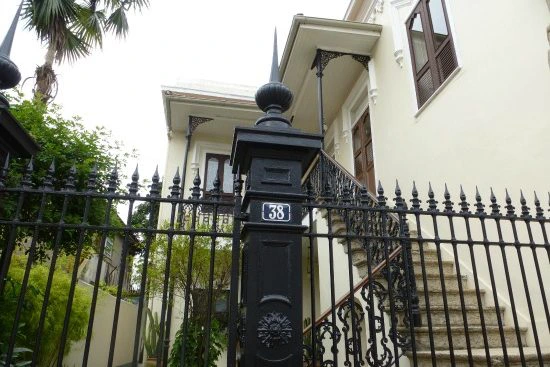Wit herenhuis met trap naar de ingang, omheind door een zwart smeedijzeren hek met nummer 38.