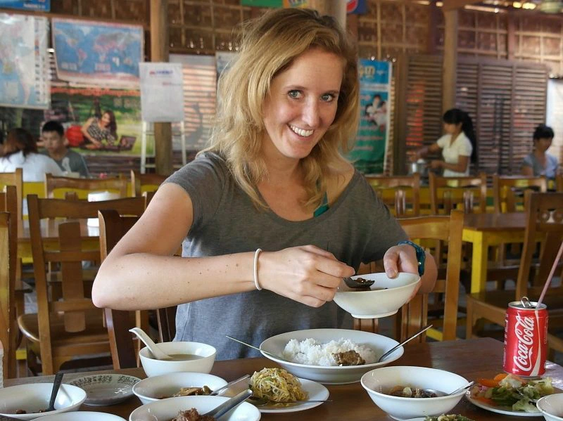 Vrouw in lokaal restaurant geniet van een maaltijd met verschillende Aziatische gerechten.