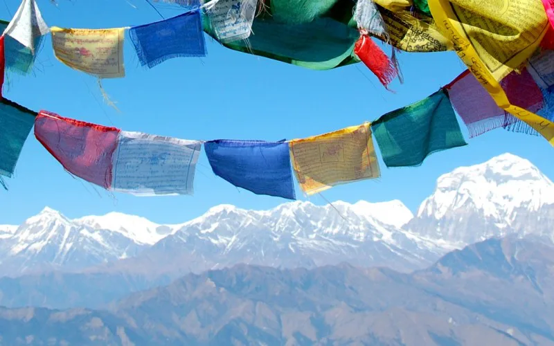 Kleurrijke gebedsvlaggen wapperen in de wind met op de achtergrond de besneeuwde toppen van de Himalaya in Nepal.