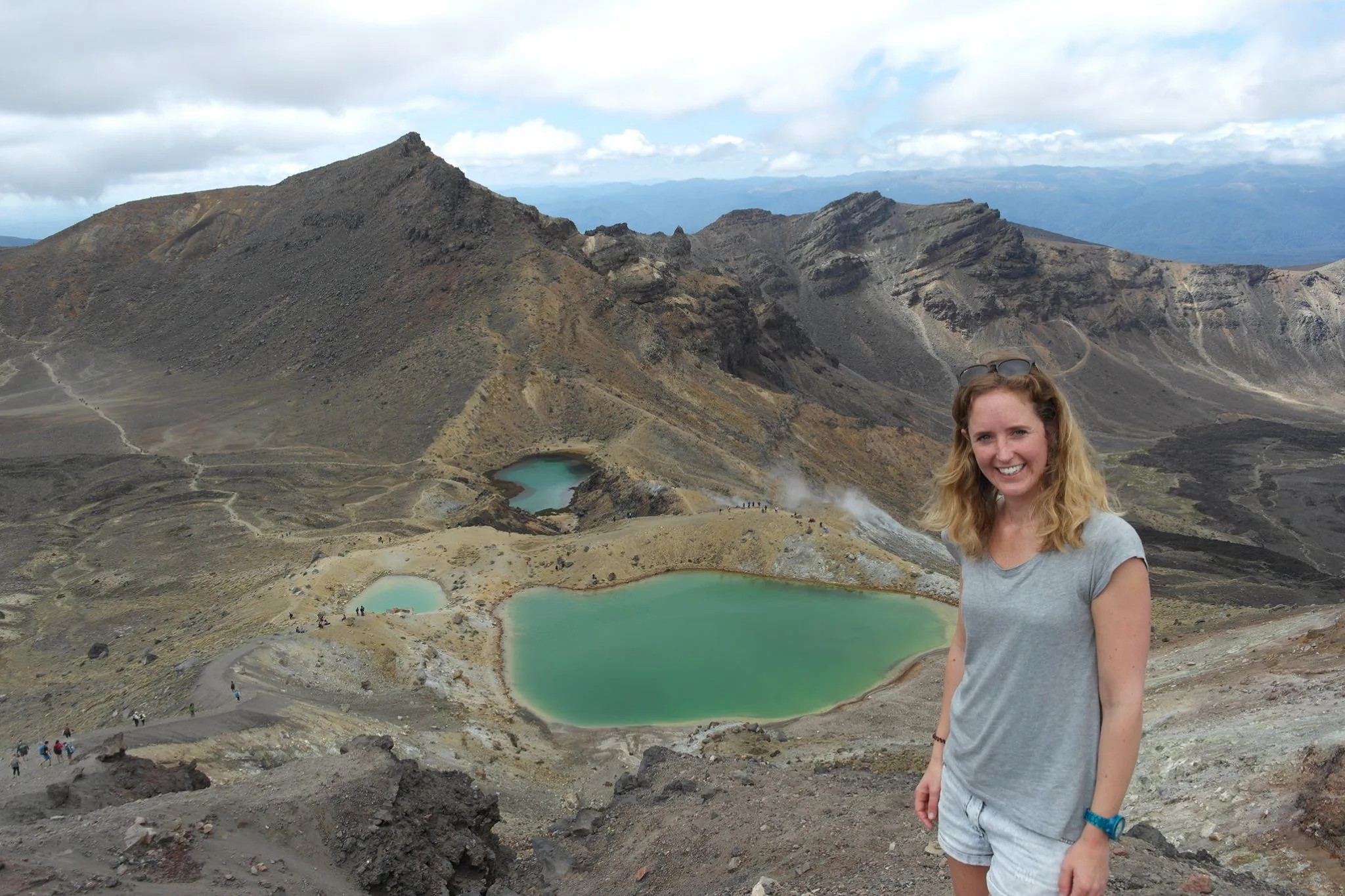 Vrouw staat op een bergpad met uitzicht op de Emerald Lakes in Tongariro National Park, Nieuw-Zeeland.