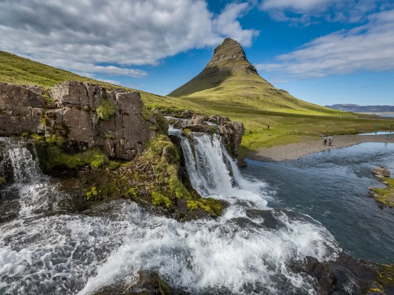 Waterval stroomt over rotsen met de iconische berg Kirkjufell op de achtergrond in IJsland.