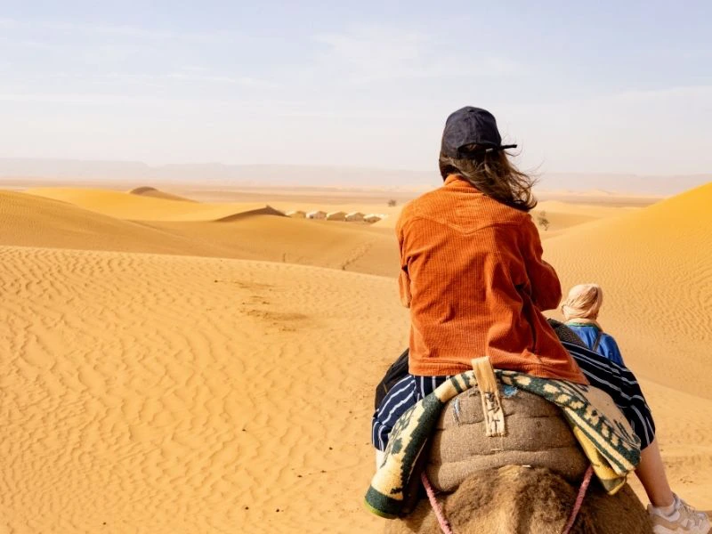 Vrouw op kameel in de woestijn van Marokko