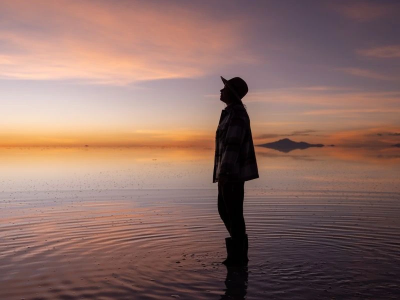 Reiziger op de zoutvlakte in Uyuni, Bolivia tijdens de zonsondergang