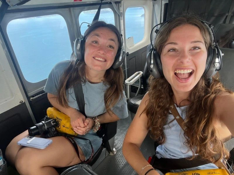 Twee lachende vrouwen met headsets in een klein vliegtuig, klaar voor een rondvlucht boven de Whitsundays bij Airlie Beach in Queensland, Australië.