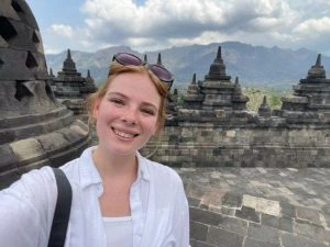 Vrouw maakt een selfie bij de Borobudur-tempel op Java, Indonesië, met stenen stoepa’s en bergen op de achtergrond.