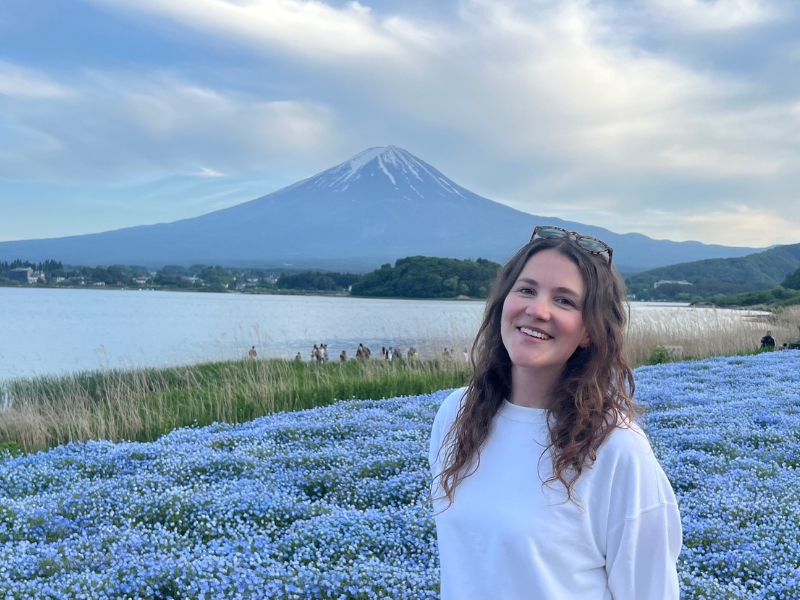 Vrouw staat in een bloemenveld met Mount Fuji op de achtergrond.