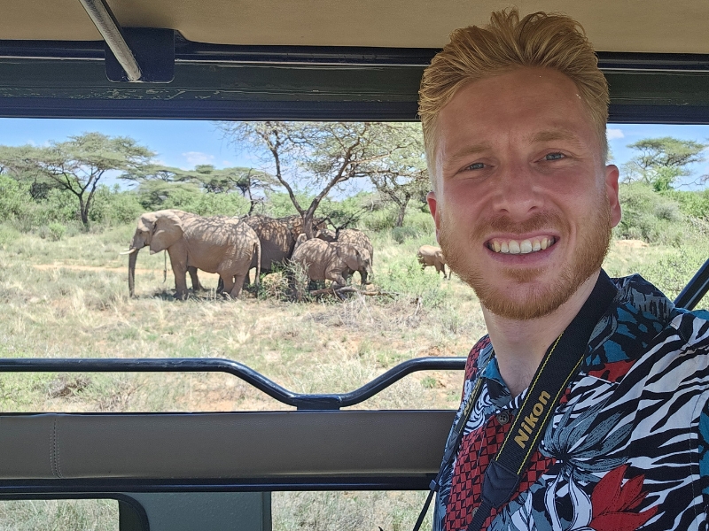 Man op safari met olifanten op de achtergrond