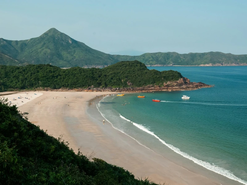 strand van Sai Kung omringd door groene heuvels en rotsen. De zee is mooi turquoise.