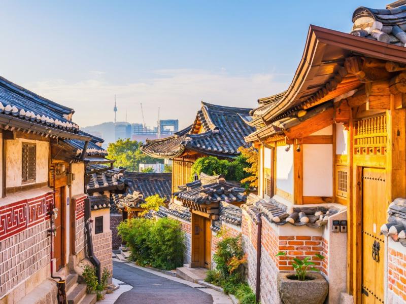 Bukchon Hanok Village in Seoul, met karakteristieke en traditionele huizen en op de achtergrond wolkenkrabbers en de Lotte Tower