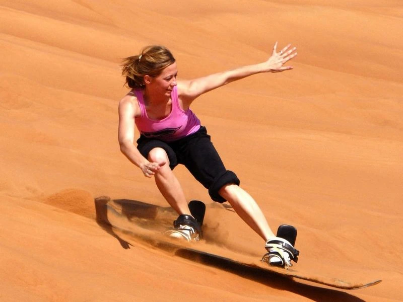 Vrouw aan het sandboarden in de duinen van Swakopmund