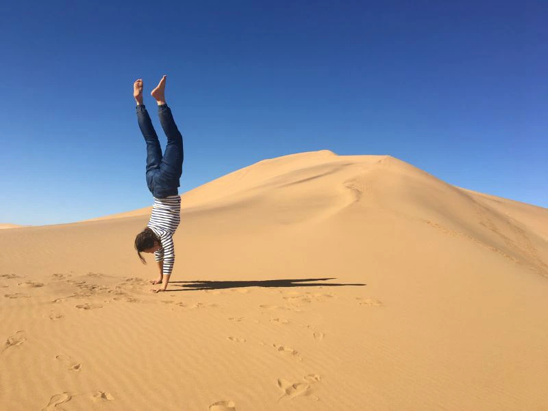 Reiziger maakt handstand in de woestijn van Namibië