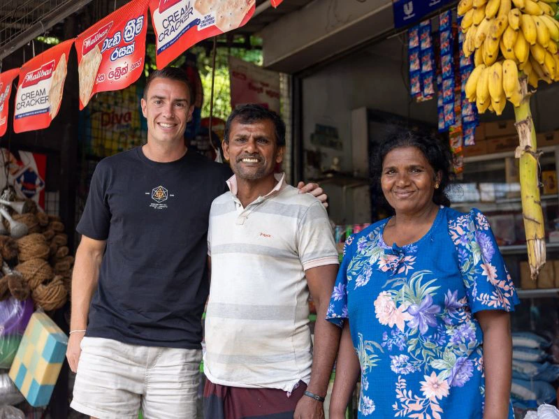Reiziger op de foto met twee Sri Lankanen voor een klein winkeltje.