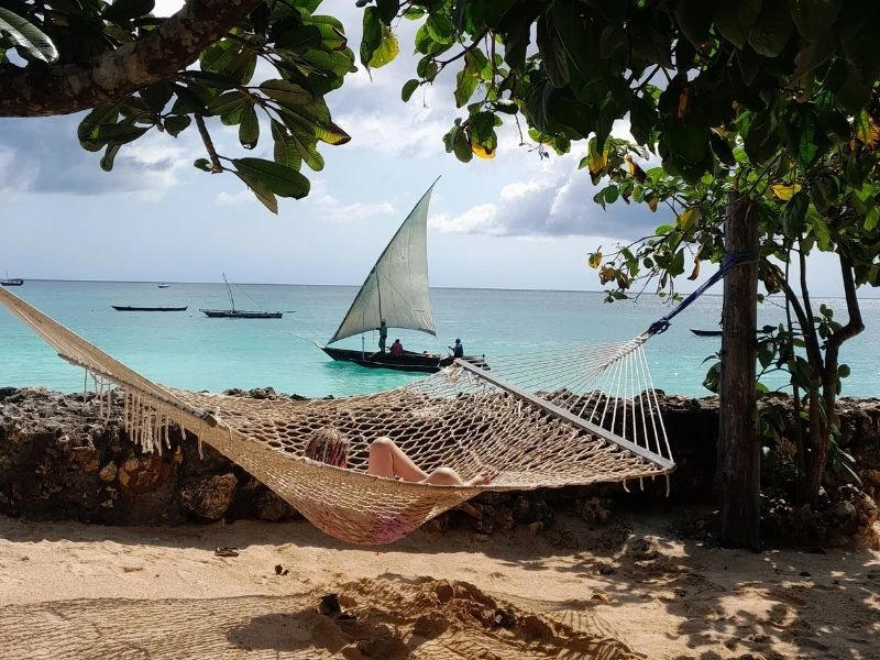 Meisje in Hangmat met uitzicht op de zee met een zeilboot