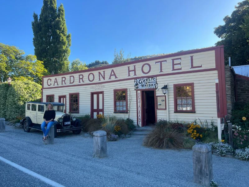 Reiziger zit op een paal voor de entree van het historische hotel in Wanaka.