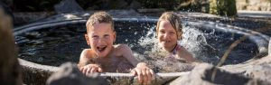Twee kinderen spelen in een waterbad in Rotorua