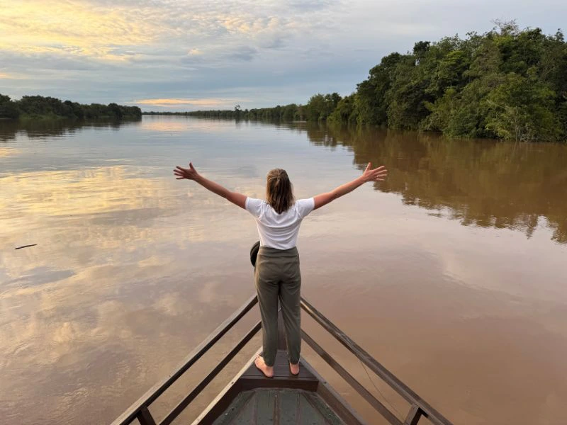 Reizigster die poseert op de nok van de boot op een grote rivier op Kalimantan