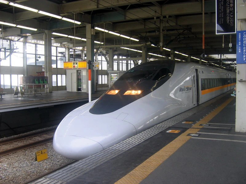 Witte Japanse hogesnelheidstrein (Shinkansen) staat stil op het perron van een modern treinstation.