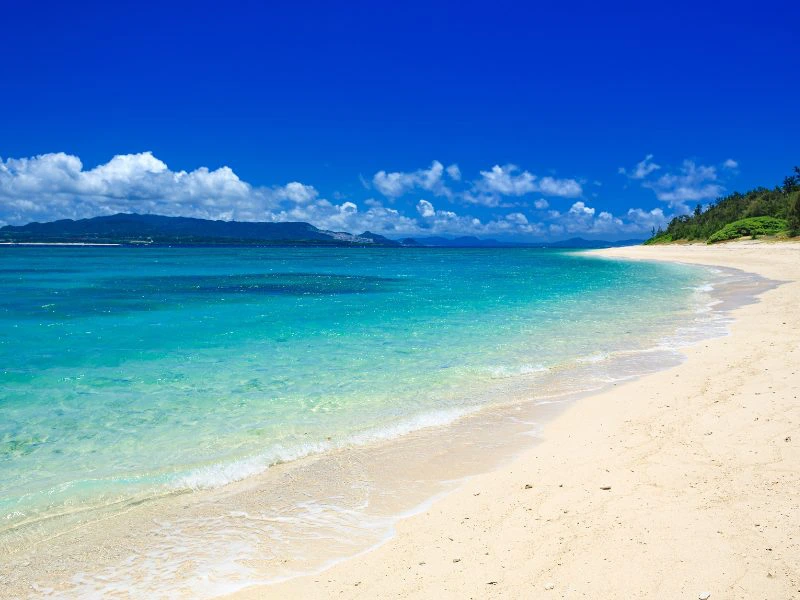 Wit zandstrand met turquoise zee en helderblauwe lucht op Okinawa, Japan.
