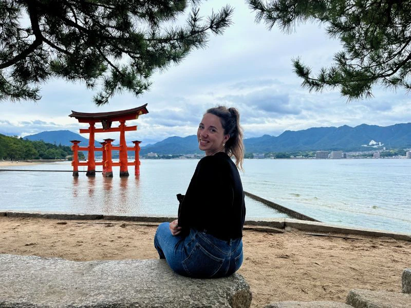 Vrouw zittend bij de rode poort in het water bij Miyajima