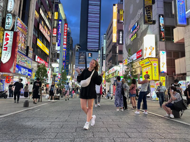Vrouw op straat in Tokyo tussen hoge gebouwen met neon verlichting