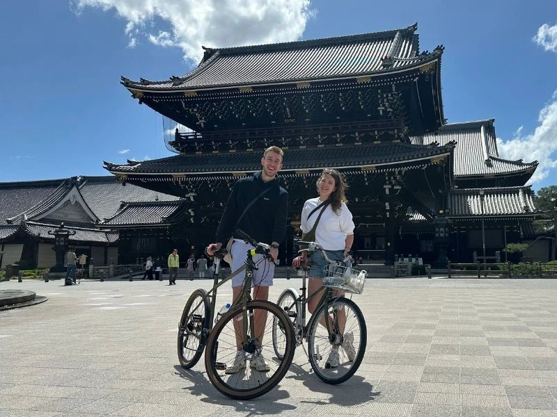 Twee mensen met de fiets staan voor een tempel in Kyoto