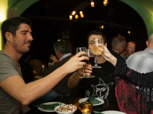 Mensen zitten in een restaurant en proosten met glazen wijn en bier boven de tafel.