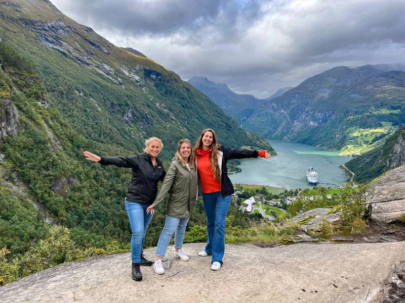 Drie reizigers lachen met het Geirangerfjord op de achtergrond.