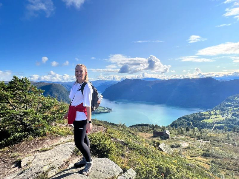 Vrouw staat op een bergtop in Noorwegen met een prachtig uitzicht.