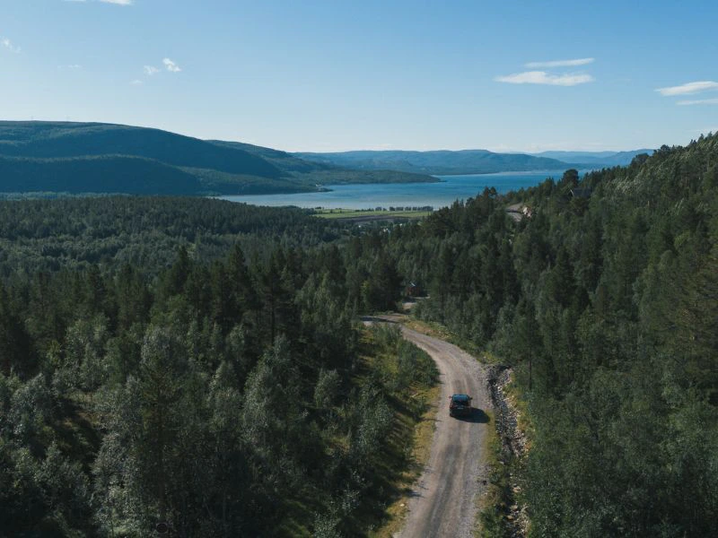 Auto rijdt door de bossen richting het water.
