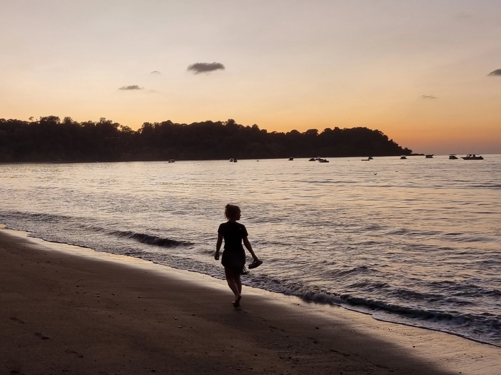 Vrouw loopt op het strand in Costa Rica bij zonsondergang