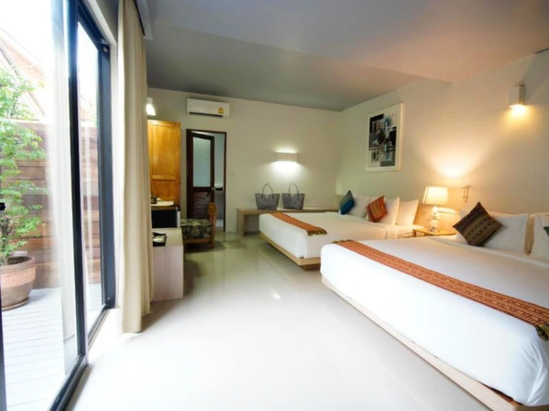 Lichte hotelkamer met twee grote bedden, moderne inrichting en schuifdeur naar buiten.