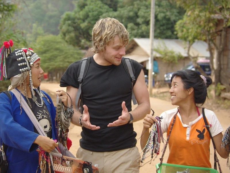 Reiziger in gesprek met twee lokale vrouwen in traditioneel kleding tijdens een wandeling in Noord-Thailand