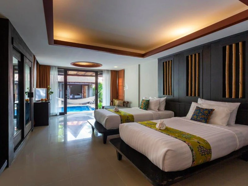 Moderne hotelkamer met twee eenpersoonsbedden, donker houten accenten, decoratieve kussens en uitzicht op een privézwembad met hangmat via grote glazen schuifdeuren.