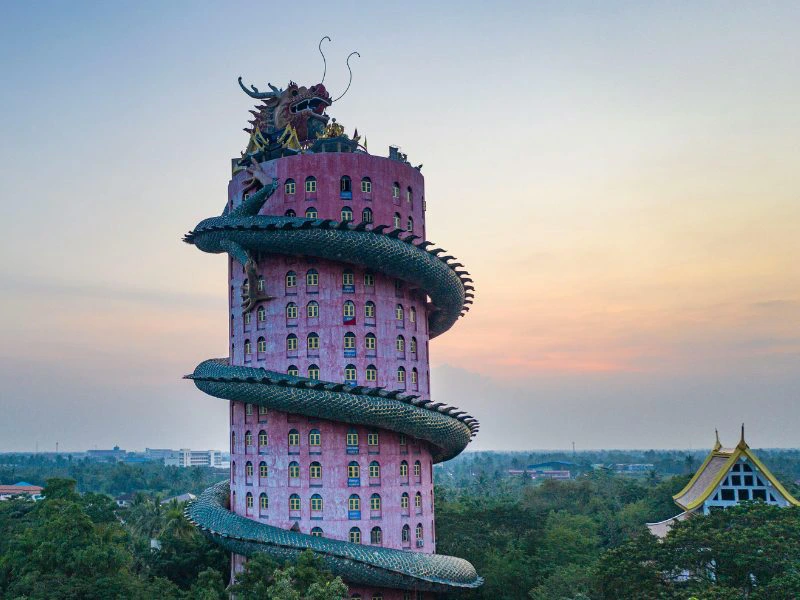 Roze hoge toren die boven gebouwen en bomen uitsteekt, met een grote groene drakenfiguur die zich om het cilindervormige gebouw slingert