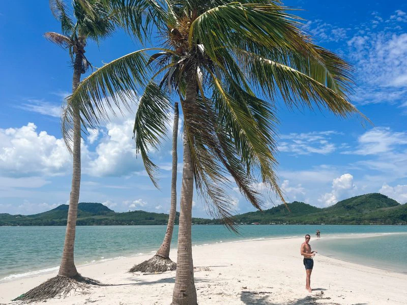 Man op een tropisch strand met palmbomen op een klein eiland in Thailand