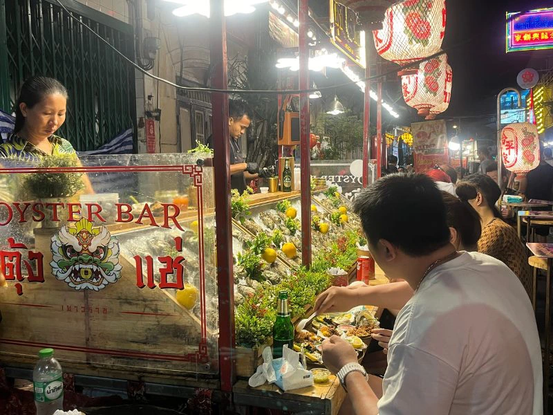 Thaise vrouw die bij een straatkraampje streetfood eet in Bangkok in Thailand
