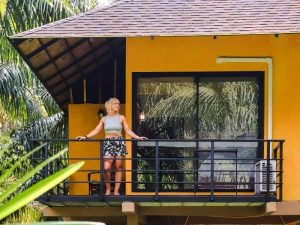 Vrouw die uitkijkt vanaf een balkon over de jungle vanuit haar community jungle lodge in Khao Sok in Thailand.