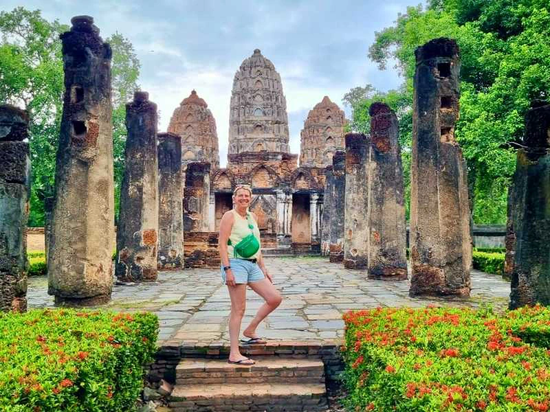 een vrouw staat voor tempelruïnes in Sukhothai