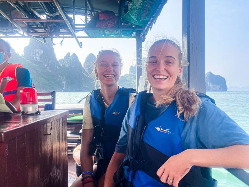 Twee lachende reizigers met zwemvesten aan op een boot.