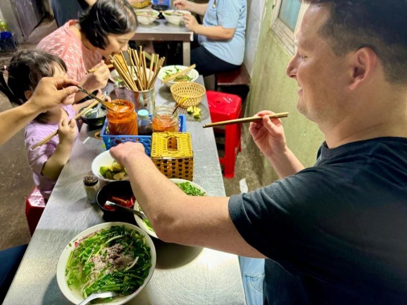 Reiziger zit tussen de locals en geniet van het de Vietnamese keuken