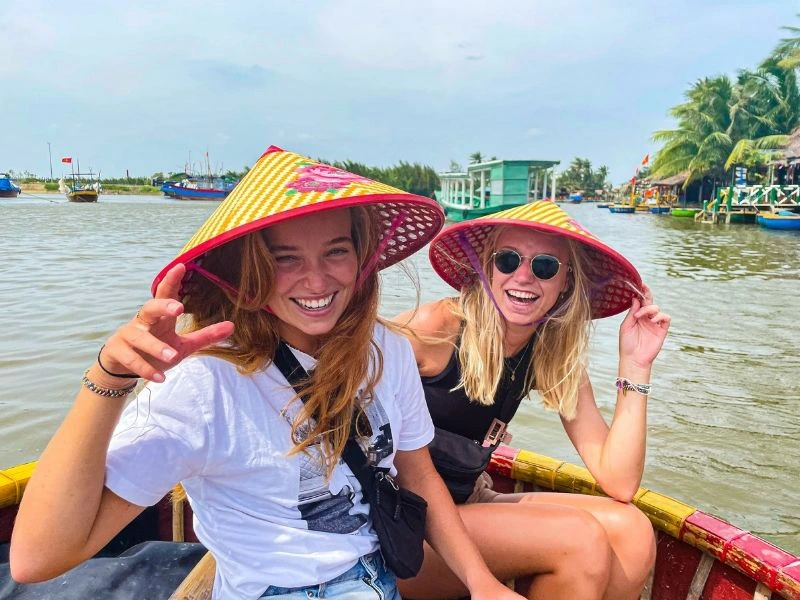 Twee vrouwen in een boot In Hoi An met een kleurrijke Non La op hun hoofd.