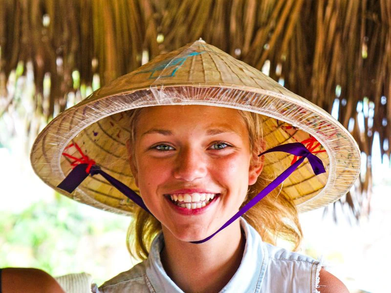 Lachende reiziger met een Non La hoed op haar hoofd.