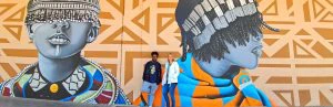 Man en een vrouw staan tegen een muur in Johannesburg. De muur is gevuld met street art.