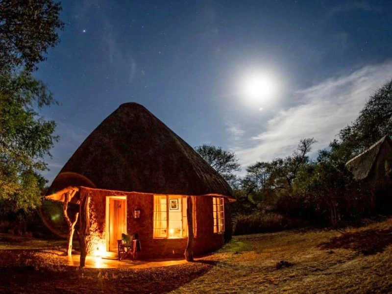 Lodge in het donker verlicht met olielamp en maan in de lucht