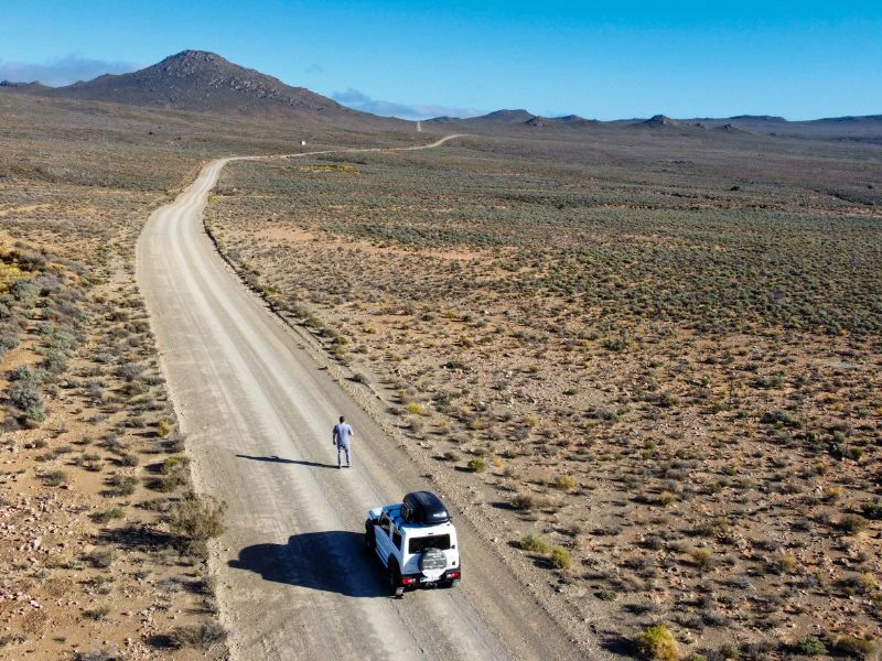 Foto van bovenaf van weg met man en auto